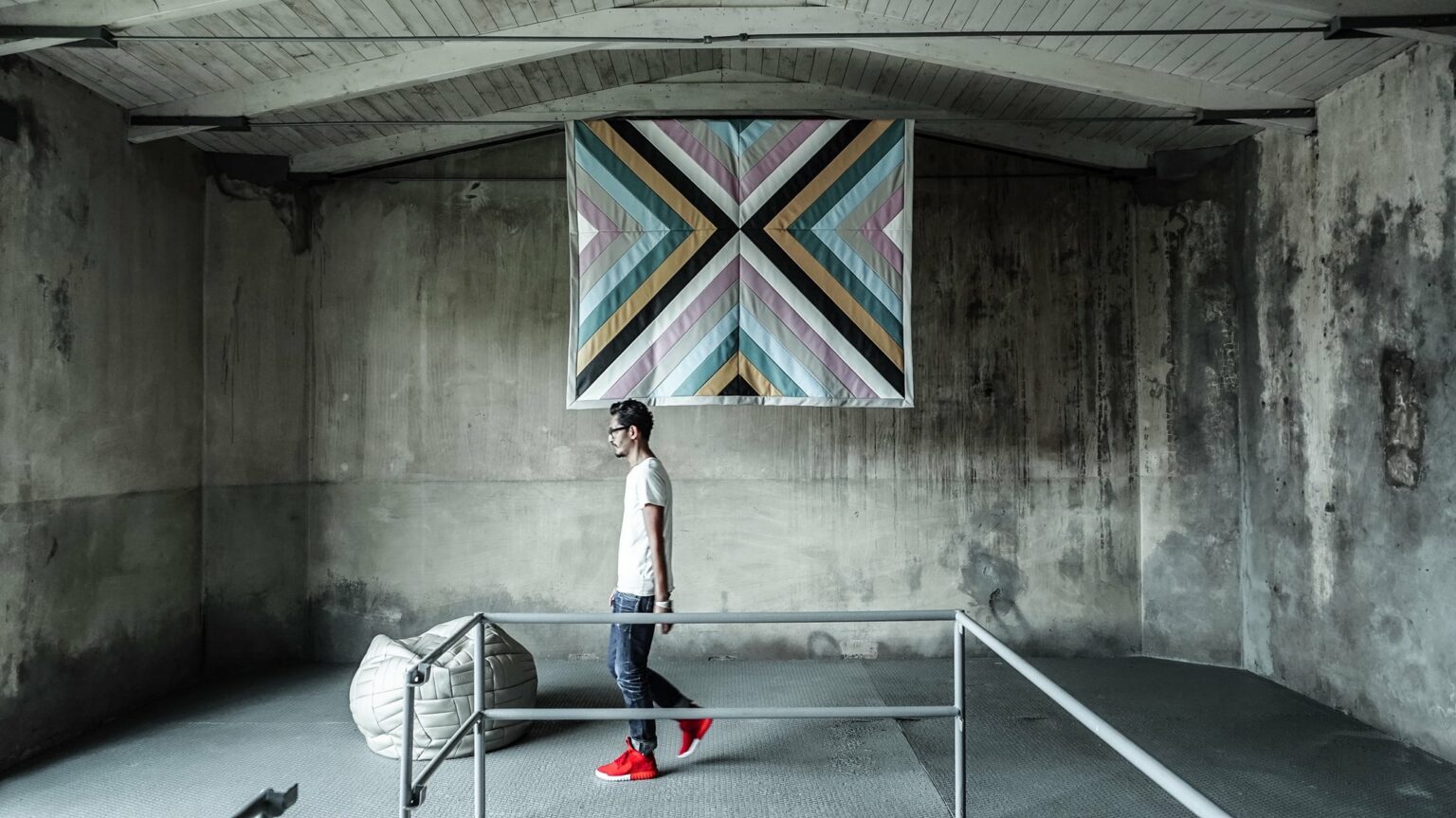Iemand loopt onder een grote quilt aan de betonwand