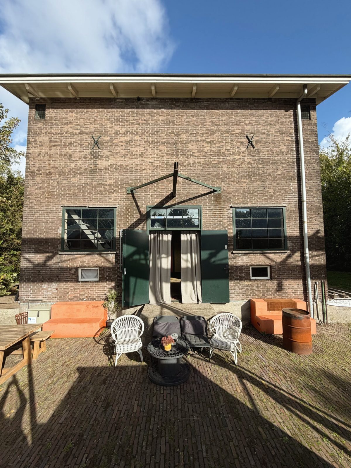 De voorgevel van het carbidgebouw in de zon, met stoelen en vuurschaal