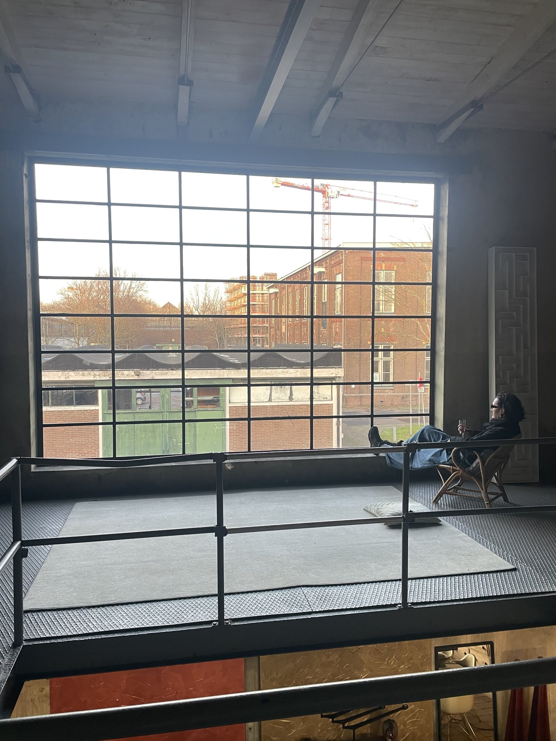 Iemand leest bij het grote raam op de eerste verdieping
